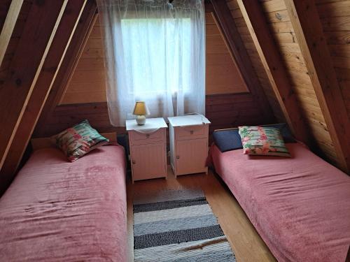 two beds in a attic room with a window at Domek Ostrowo in Ostrowo