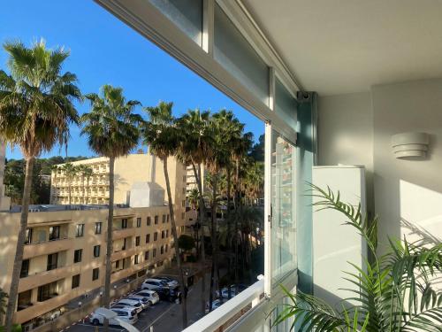 einen Balkon mit Blick auf eine Stadt mit Palmen in der Unterkunft Sunny Seaview Apartment in Torremolinos