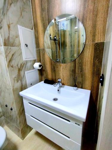 uma casa de banho com um lavatório branco e um espelho. em ЖК Crystal em Karaganda