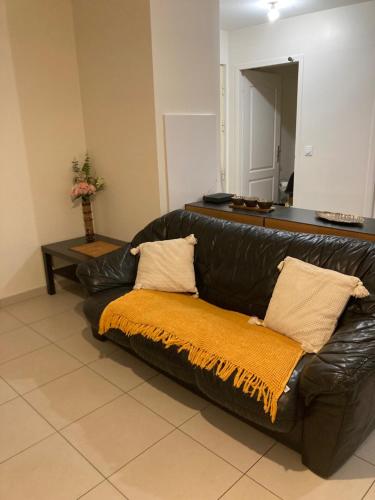 Un sofá de cuero negro con una manta naranja. en T2 centre ville RERB pour 2-4 personnes, en Palaiseau