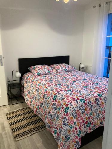 1 dormitorio con 1 cama con un edredón colorido en T2 centre ville RERB pour 2-4 personnes, en Palaiseau