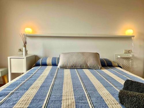 ein Schlafzimmer mit einem Bett mit einer blau-gelben gestreiften Decke in der Unterkunft Apartamento Les Orenetes in Espinelvas