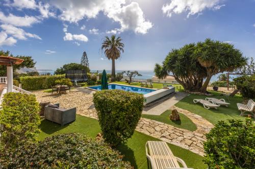 a garden with a swimming pool and palm trees at Seaside Retreat Casa Romana in Luz