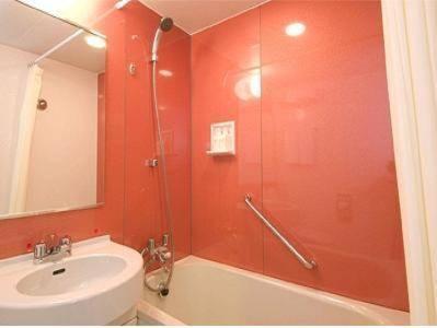 a bathroom with red walls and a sink and a shower at Smile Hotel Sendai Izumi IC in Sendai