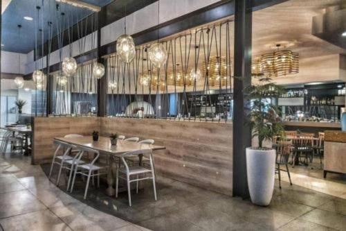 un restaurante con mesa y sillas y un bar en Cosy luxurious apartment, en Pretoria