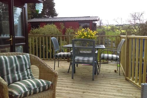een patio met stoelen en een tafel met bloemen bij Anne's Lodge Caerberis Holiday Park, dog friendly in Builth Wells