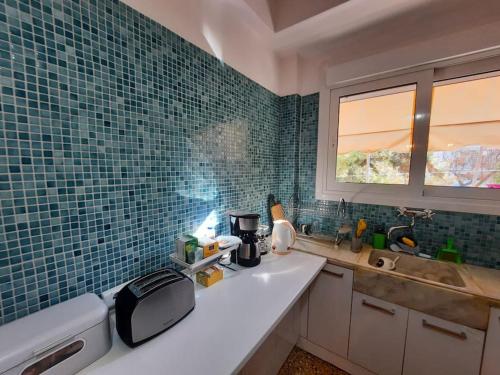 a kitchen with a sink and green tiled walls at Apartment near Acropolis in Athens