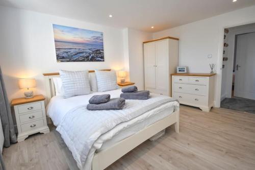 1 dormitorio con 1 cama blanca grande y 2 lámparas en Dexters Den - Sea views, yards from Beach, en Amble
