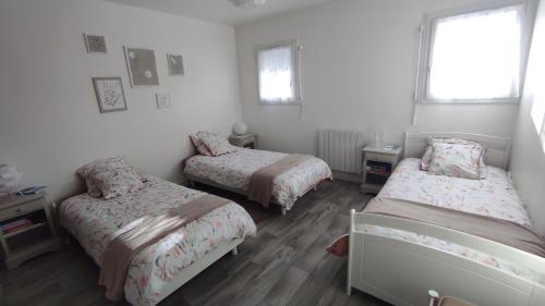 a bedroom with three beds and a window at Les Bordaiseries in La Réorthe
