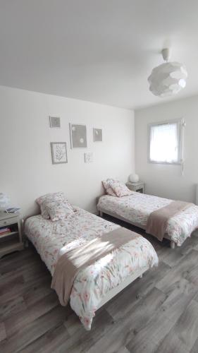 two beds in a white room with wooden floors at Les Bordaiseries in La Réorthe