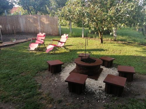 a backyard with a fire pit and chairs and a tree at Kossuth Vendégház in Mátraderecske