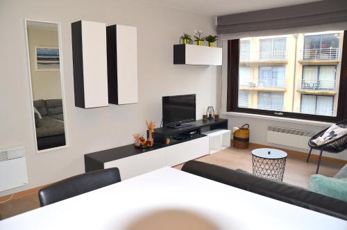 a living room with a couch and a television at SeeYou@Sea in Nieuwpoort