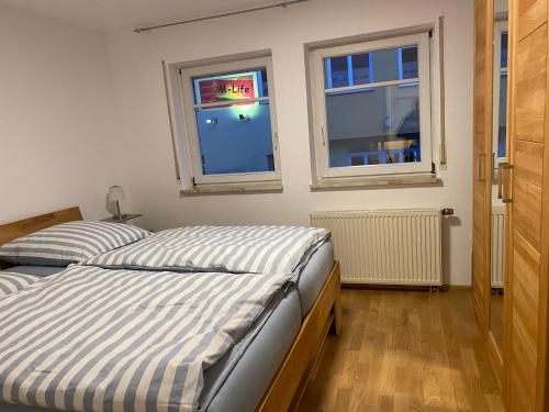 two beds in a bedroom with two windows at Ferienwohnung am Obertor in Pfullendorf