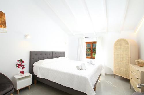 a white bedroom with a bed and a window at Jaume Romana by Vida Villas in Pollença