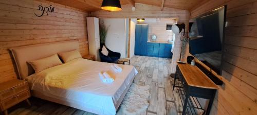 1 dormitorio con 1 cama y pared de madera en Imbar relaxing wood log cabin, en Jaffa-Tel Aviv