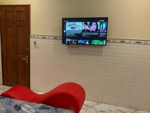 a tv on a wall with a red bench and a chair at Nhà Nghỉ Tuyết Minh in Xóm Mỹ Thanh