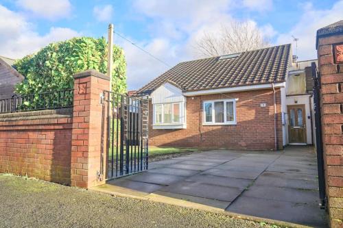 a brick house with a wrought iron gate at Bespoke Bungalow Salford Quays - Garden, WiFi and Parking in Manchester