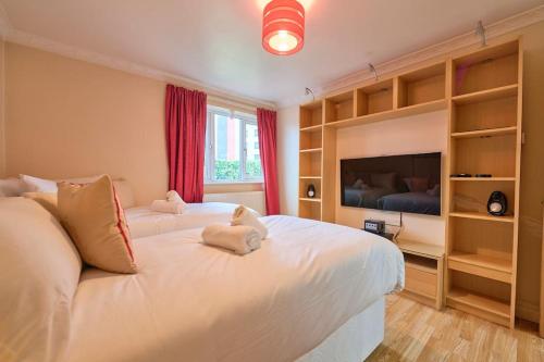a bedroom with two white beds and a flat screen tv at Bespoke Bungalow Salford Quays - Garden, WiFi and Parking in Manchester