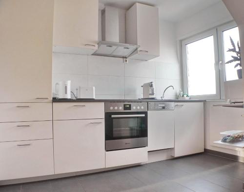 een witte keuken met een fornuis en een wastafel bij Modernes, zentrales Apartment in Troisdorf, Region Köln Bonn, maximal für 4 Personen, Parkplatz & Netflix inklusive in Troisdorf