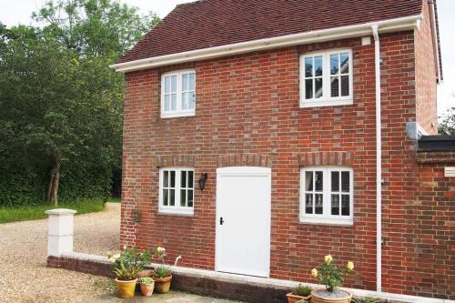 a red brick house with a white door at Stablehurst Cottage in West Hoathley