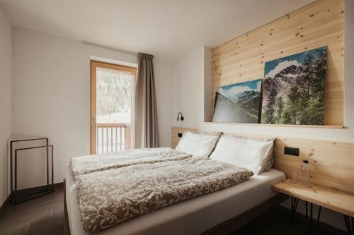a bedroom with a bed with a wooden wall at Bonvivar Mountain Guesthouse in Livigno