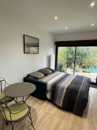 une chambre avec un lit, une table et des chaises dans l'établissement Le Méridien, studio rénové avec terrasse, 8 min à pieds du centre ville, à Villers-sur-Mer