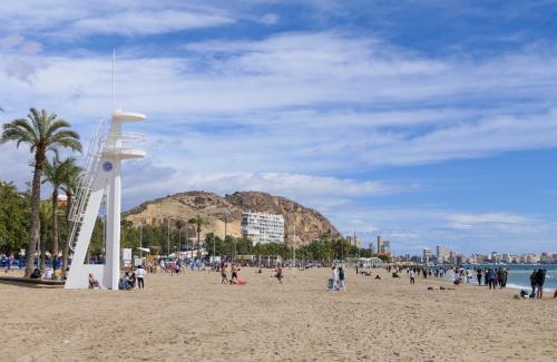 eine Gruppe von Menschen am Strand mit einem Uhrturm in der Unterkunft Luxury Apartment Turquesa Del Mar in Alicante