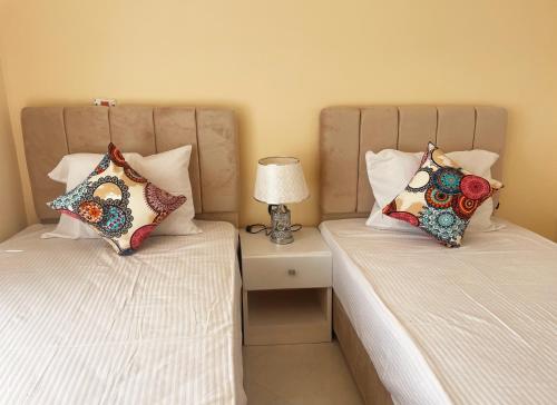 two beds in a bedroom with a lamp on a night stand at Karima House in Luxor