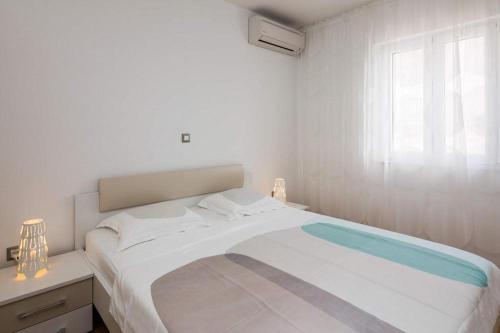 a white bedroom with a large bed and a window at Apartments Vista Bol in Bol