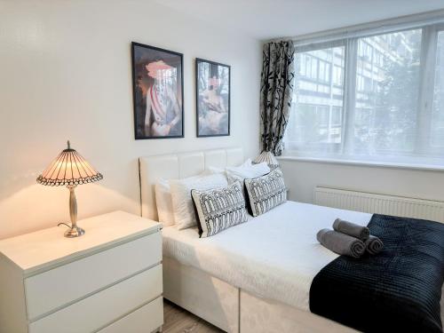 a bedroom with a bed with a lamp and a window at Modern 3Bedroom 3 Bathroom Apartment with Private Garden- Maida Vale in London