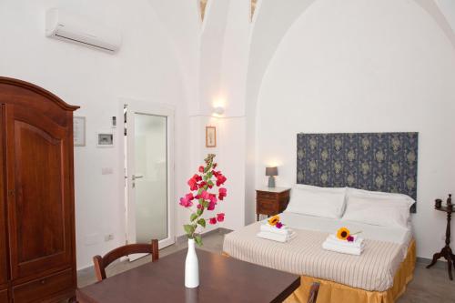 a bedroom with a bed and a table with flowers on it at La Corte Della Luce in Ugento