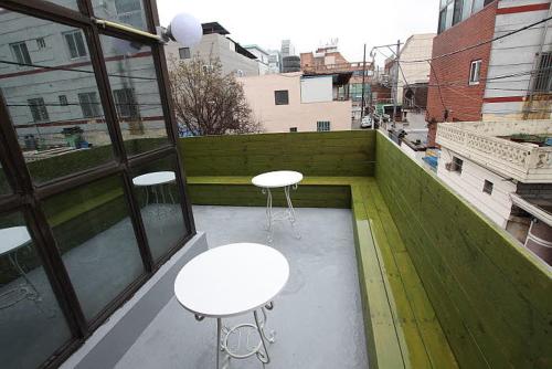 a balcony with two tables and two stools on it at Gyeongju Friend Guesthouse in Gyeongju