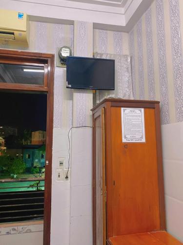 a room with a television on a wall with a door at Nhà Nghỉ Ánh Ngọc in Hue