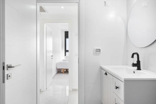 a white bathroom with a sink and a mirror at Luxury Flat with Balcony & Ocean View by torohome in Ashdod