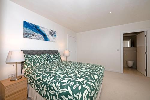 een slaapkamer met een bed met een groene en witte sprei bij Cosy Apartment in Central London in Londen