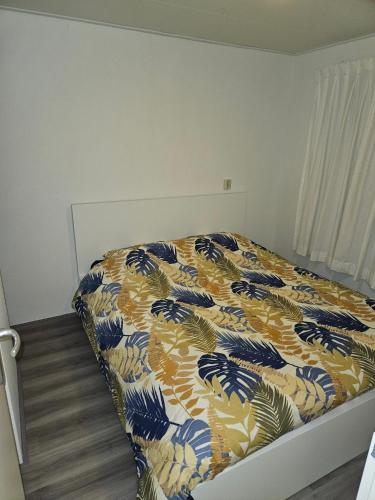 a bedroom with a bed with a blanket on it at Chalet "Aan ut water" Elburg in Biddinghuizen