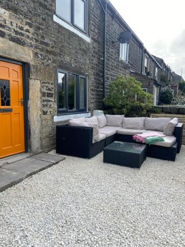 a couch sitting in front of a brick building at Pretty little cottage in the peaks in Hadfield