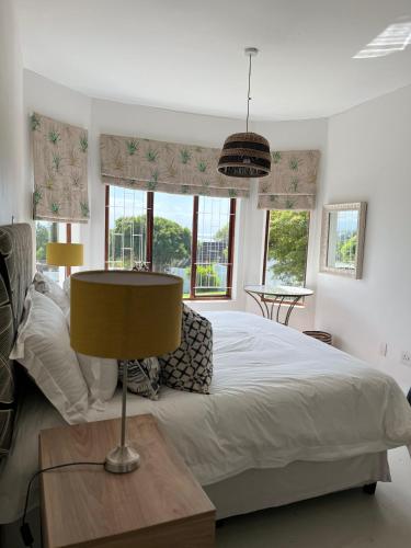 a bedroom with a bed and a table with a lamp at Living Waters in St Francis Bay