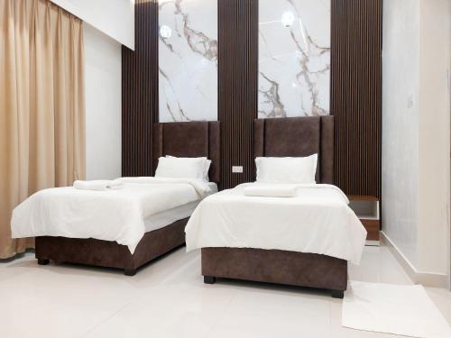 Mabahj Garnatha Hotel Apartments في صحار: غرفة نوم بسريرين مع شراشف بيضاء