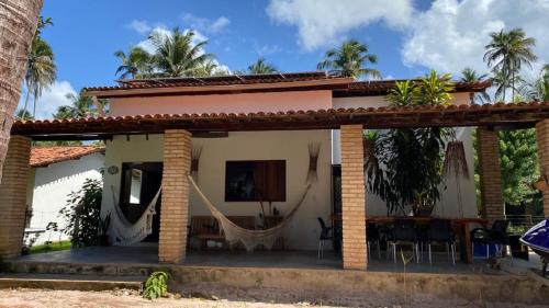a house with a hammock in front of it at A Casa de Ponta-Simplicidade e Requinte -Estrutura Completa a 150m da praia in Maragogi