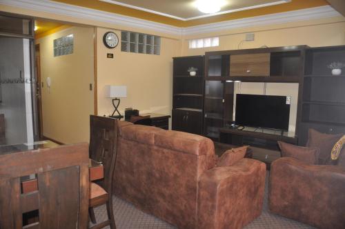 ein Wohnzimmer mit einem Sofa und einem Flachbild-TV in der Unterkunft COMODORO DEPARTAMENTOS in Oruro