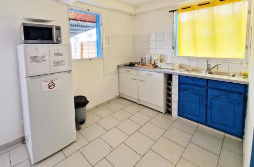 uma cozinha com um frigorífico branco e armários azuis em appartement T2 avec jacuzzi em Baie-Mahault