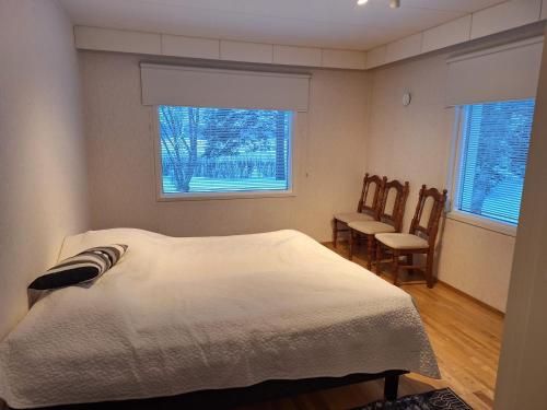 a bedroom with a bed and two chairs and two windows at Villa Lumia in Paranen