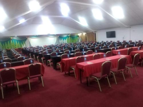 a large room with red tables and chairs and a screen at Lysak Haven Park hotel in Machakos