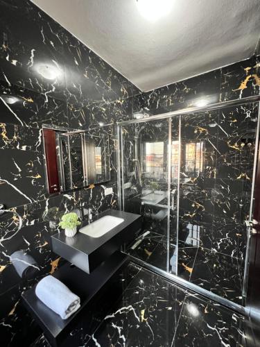 baño de mármol negro con lavabo y ducha en North Star Hostel en Shkodër