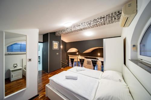 a bedroom with a white bed and a kitchen at Šanić Apartments 543/a in Lopar