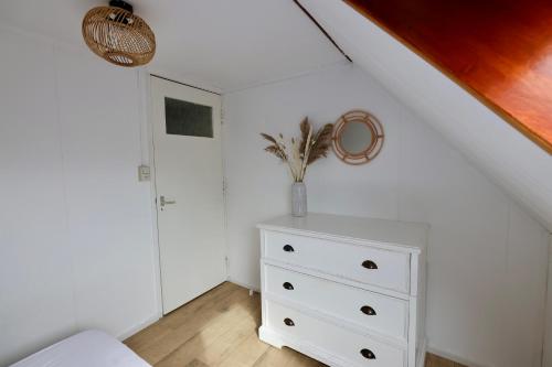 een slaapkamer met een wit dressoir en een trap bij Dubbelduyn vakantie boerderij Callantsoog in Callantsoog