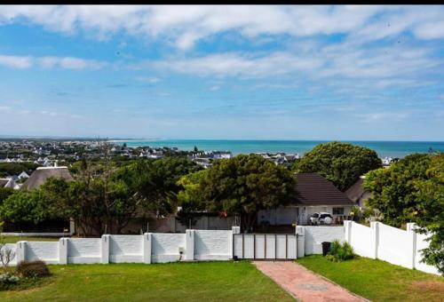 a white fence in a yard with a view of the ocean at Living Waters in St Francis Bay