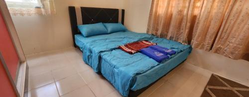 uma pequena cama com lençóis azuis num quarto em Hayyan Homestay em Kuantan