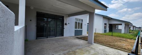 a white house with a black garage door at Hayyan Homestays in Kuantan
